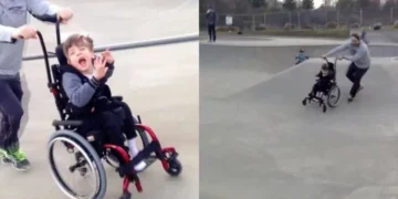 Un padre empuja a su hijo en silla de ruedas por un skatepark para que pueda patinar