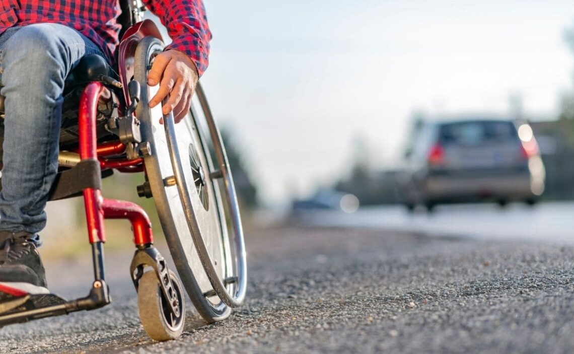 Persona con discapacidad en silla de ruedas por una acera