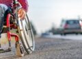 Persona con discapacidad en silla de ruedas por una acera