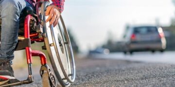 Persona con discapacidad en silla de ruedas por una acera
