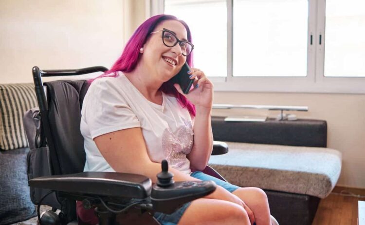 Persona con discapacidad física en silla de ruedas habla por teléfono