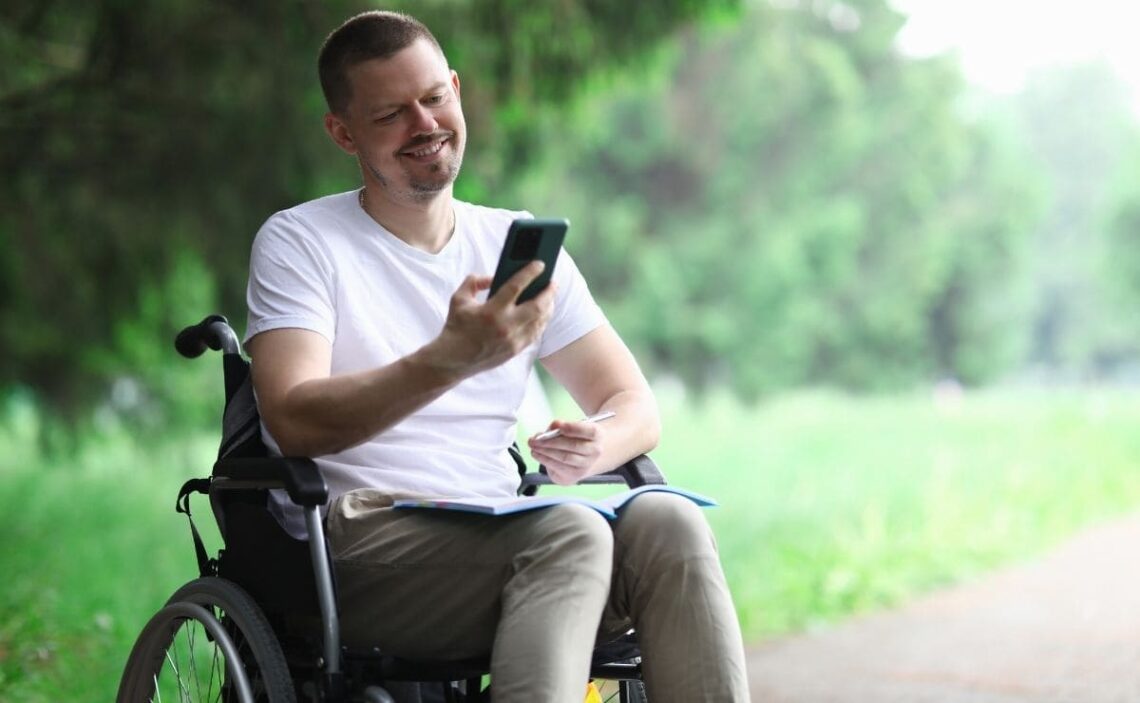 Persona con discapacidad en silla de ruedas consulta su teléfono móvil