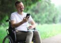 Persona con discapacidad en silla de ruedas consulta su teléfono móvil