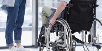 Persona en silla de ruedas con discapacidad espera en una estación