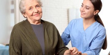 Persona mayor en situación de dependencia siendo ayudada por una profesional