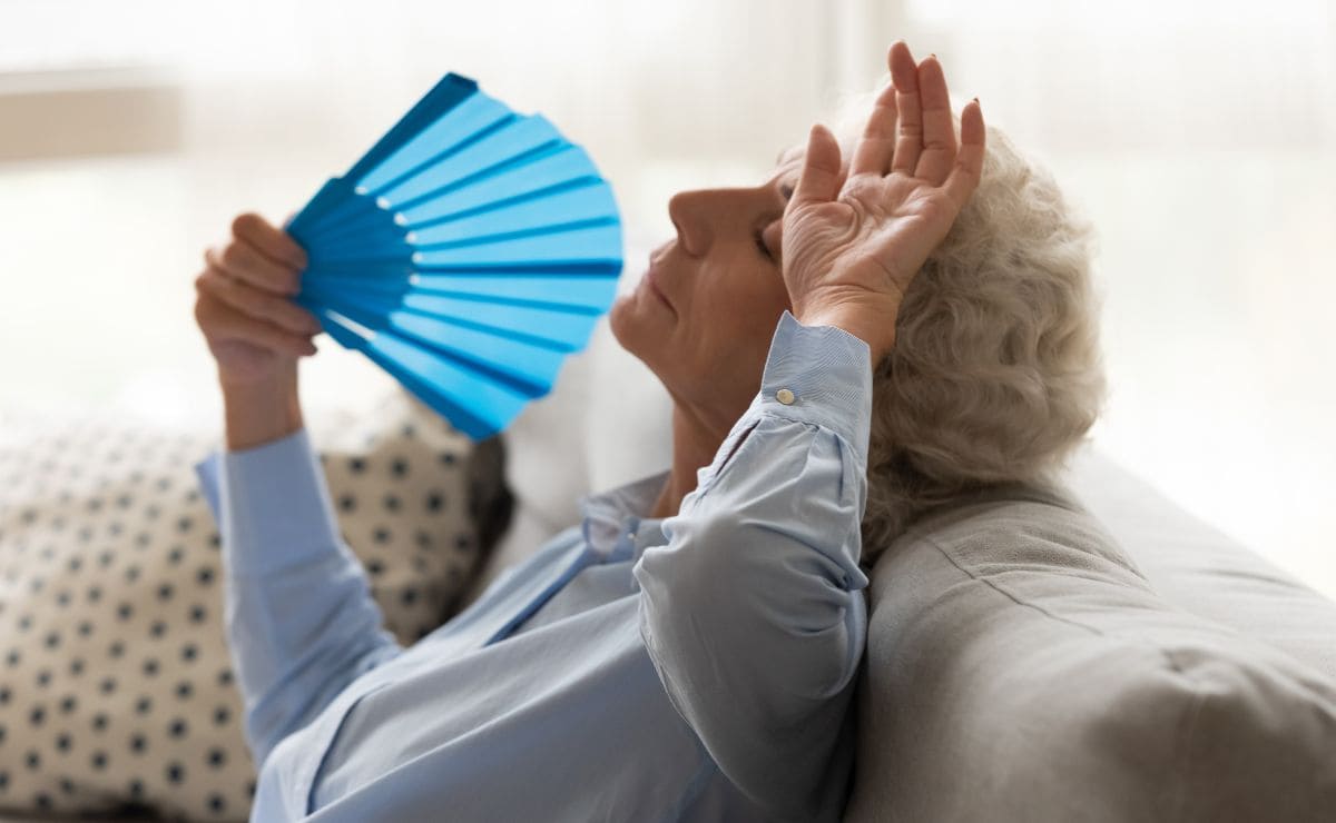 Una mujer mayor se abanica en el sofá de casa ante las altas temperaturas