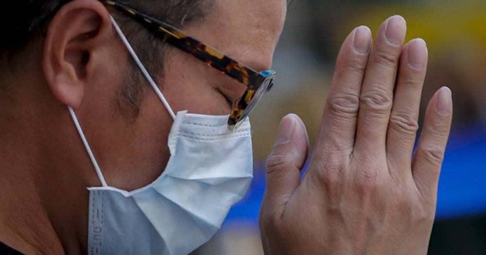 Persona rezando con mascarilla durante la crisis del Coronavirus