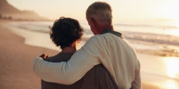 Personas mayores da un paseo por la playa durante un viaje