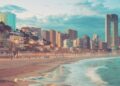 Playa de Benidorm en primer plano y al fondo los rascacielos de la ciudad