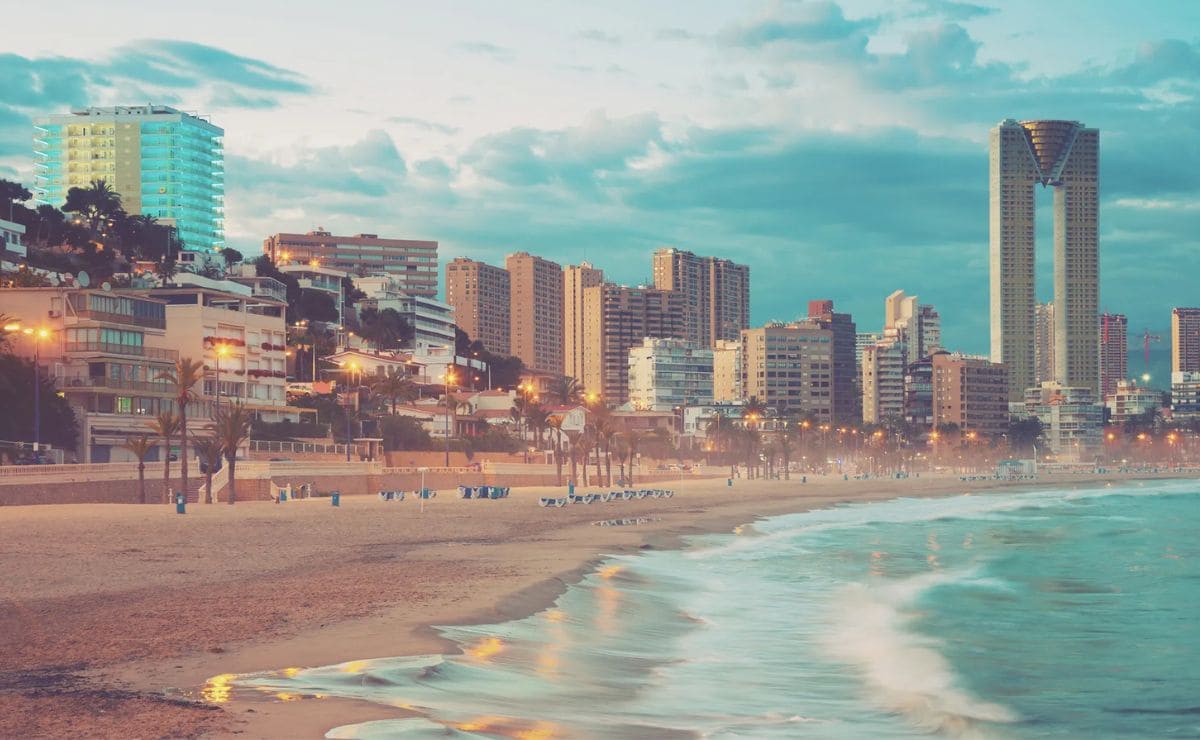 Playa de Benidorm en primer plano y al fondo los rascacielos de la ciudad