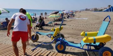 Servicios de emergencia tira de una silla de ruedas en la playa
