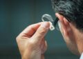 Un hombre se coloca el audífono, dispositivo electrónico para mejorar el sonido