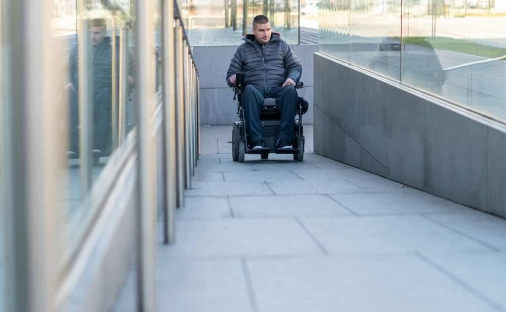 Persona en silla de ruedas avanza por una rampa que cumple con los nuevos criterios de accesibilidad