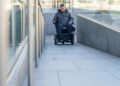 Persona en silla de ruedas avanza por una rampa que cumple con los nuevos criterios de accesibilidad