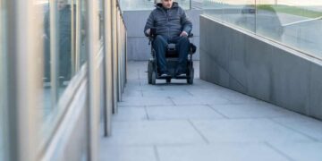 Persona en silla de ruedas avanza por una rampa que cumple con los nuevos criterios de accesibilidad