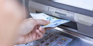 Persona retirando dinero de un cajero para cobrar el paro o ERTE