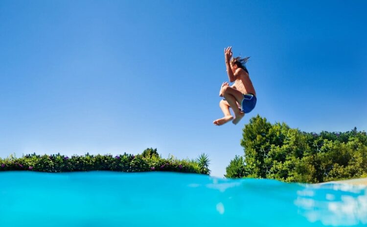 Joven saltando a la piscina haciendo una zambullida