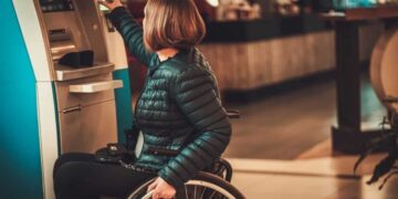 Persona en silla de ruedas saca dinero en un cajero
