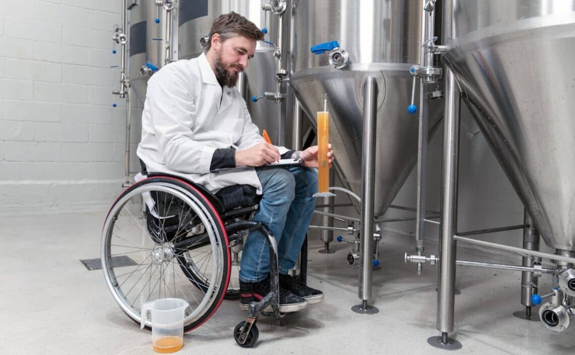 Trabajador con discapacidad en silla de ruedas analiza con una probeta