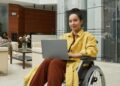Mujer en silla de ruedas trabajando desde el ordenador portátil