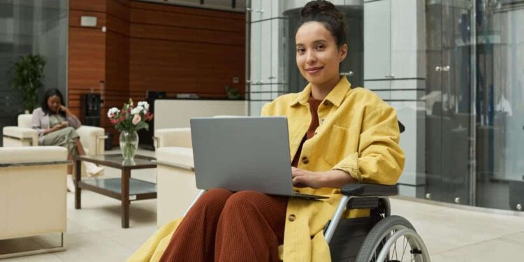 Mujer en silla de ruedas trabajando desde el ordenador portátil