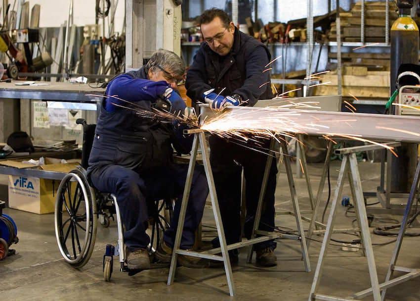 Persona en silla de ruedas soldando en su empleo