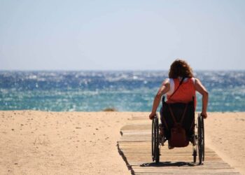 Mujer en silla en la playa, turismo accesible