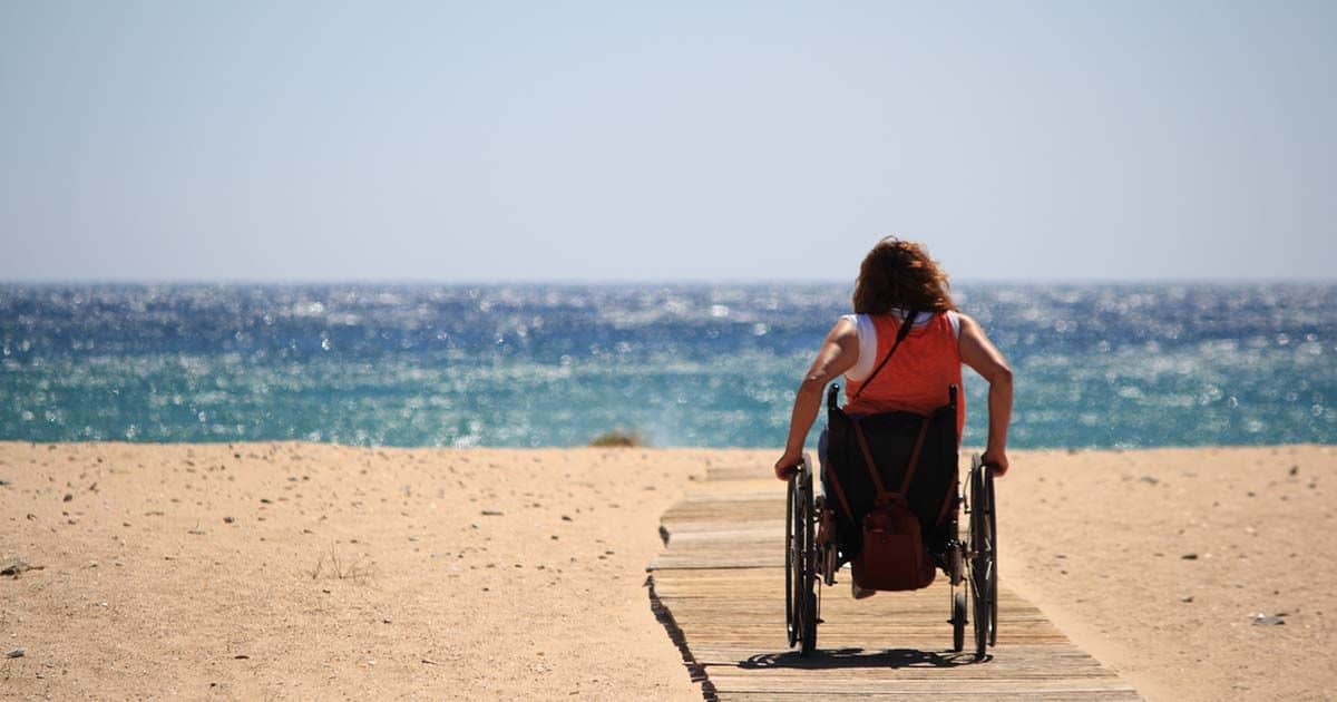 Mujer en silla en la playa, turismo accesible