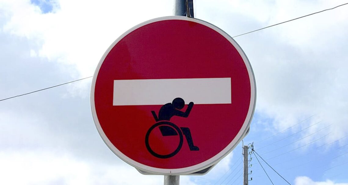 usuario de silla de ruedas aguantando señal de prohibicion