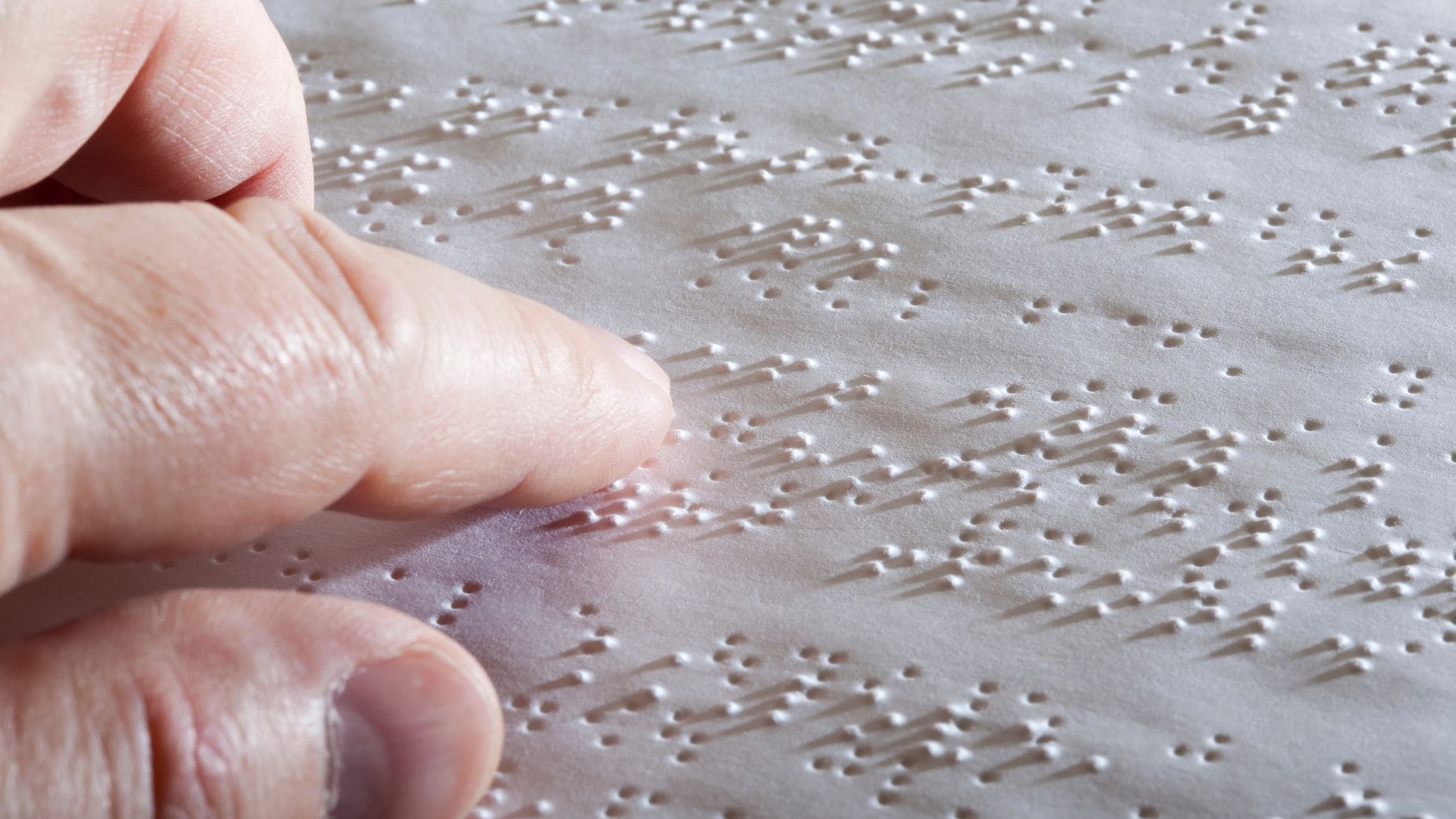 Una persona con discapacidad visual leyendo en braille