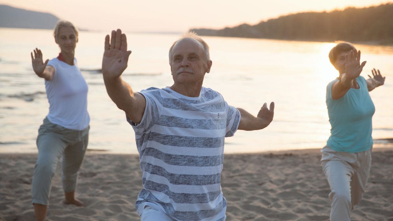 Personas mayores haciendo taichí en la playa